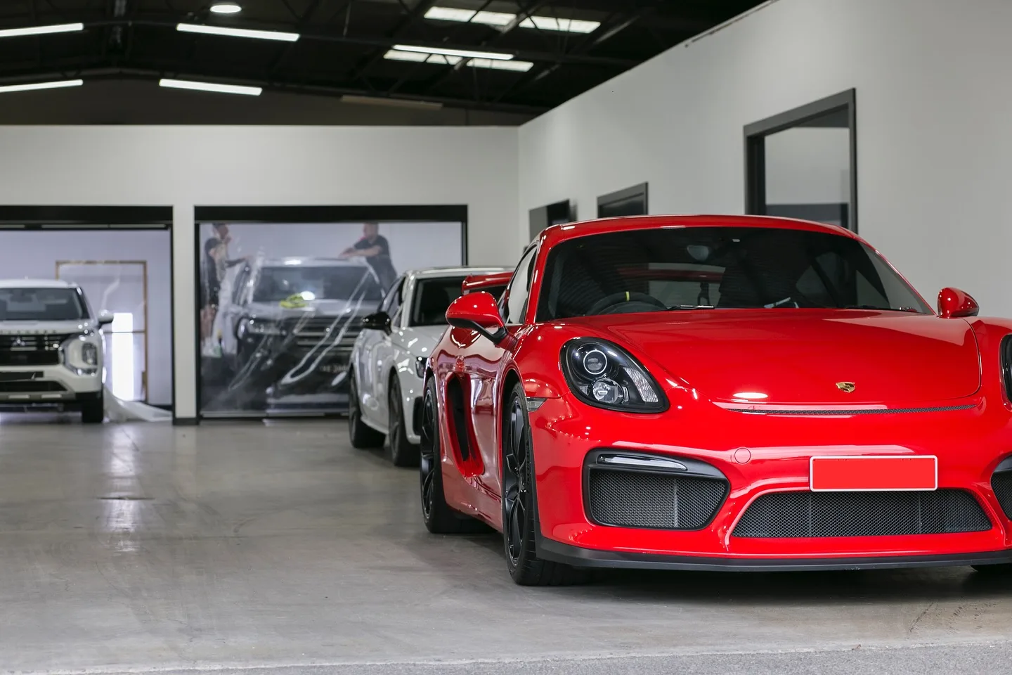The Elite Finish studio in Somerton Park, a red Porsche Cayman GT4 in front and paint protection film being fitted in the bay behind