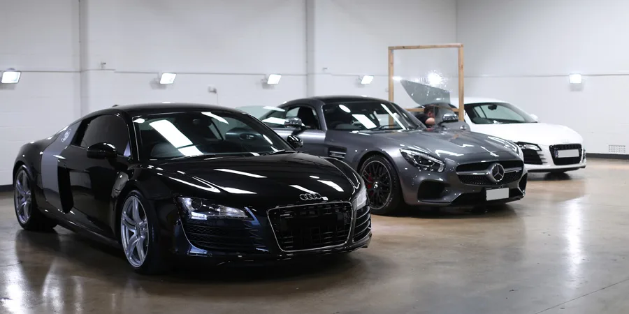 A black Audi R8, a grey Mercedes-AMG GT and a white Audi R8 lined up in the studio