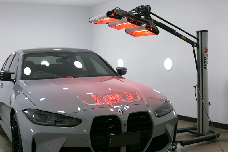 Infrared lamps curing a ceramic coating on a BMW M3