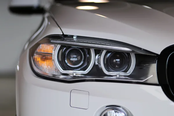 A clear, protected headlight on a white BMW