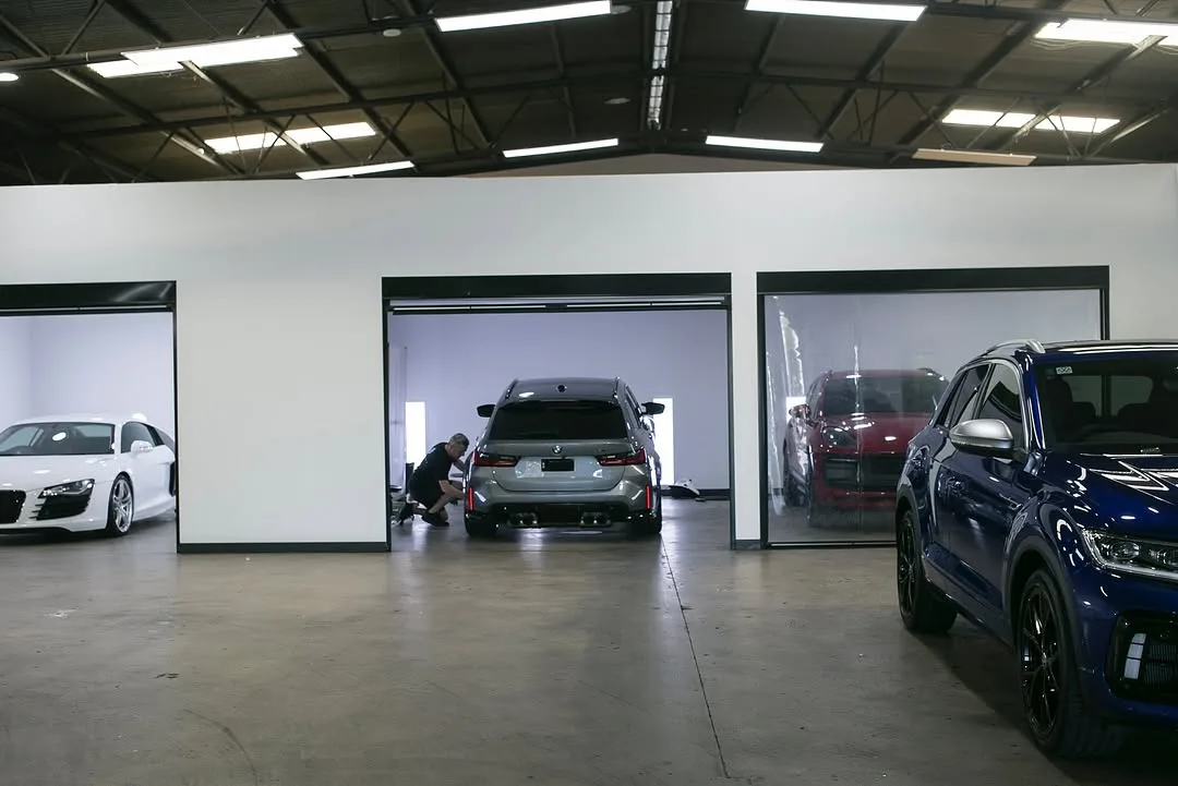 The Elite Finish studio's three bays, a white Audi R8 on the left and a grey BMW wagon being worked on in the middle